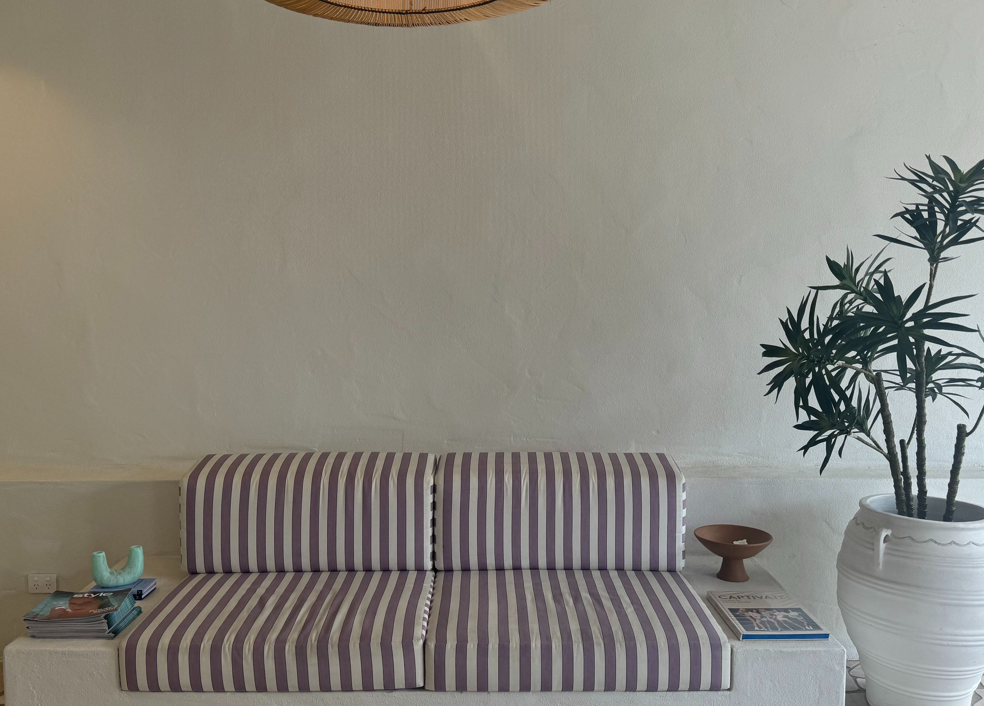 Striped couch and potted plant at Farrah Studio, New Farm, Queensland, AU creating a serene ambiance.