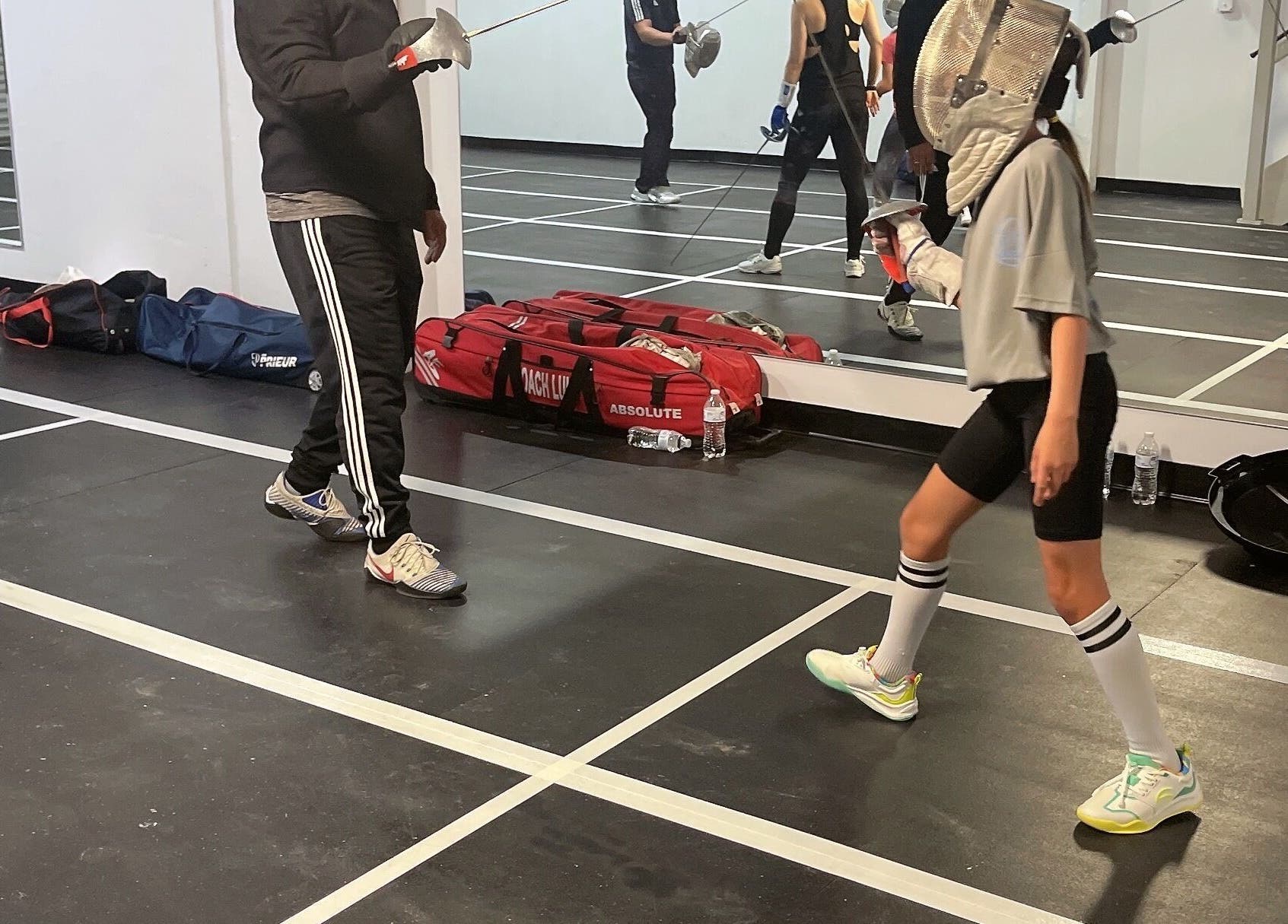 Fencing lesson at Fence MI Fencing Academy in Las Vegas, Nevada, US, showcasing student and coach in action.