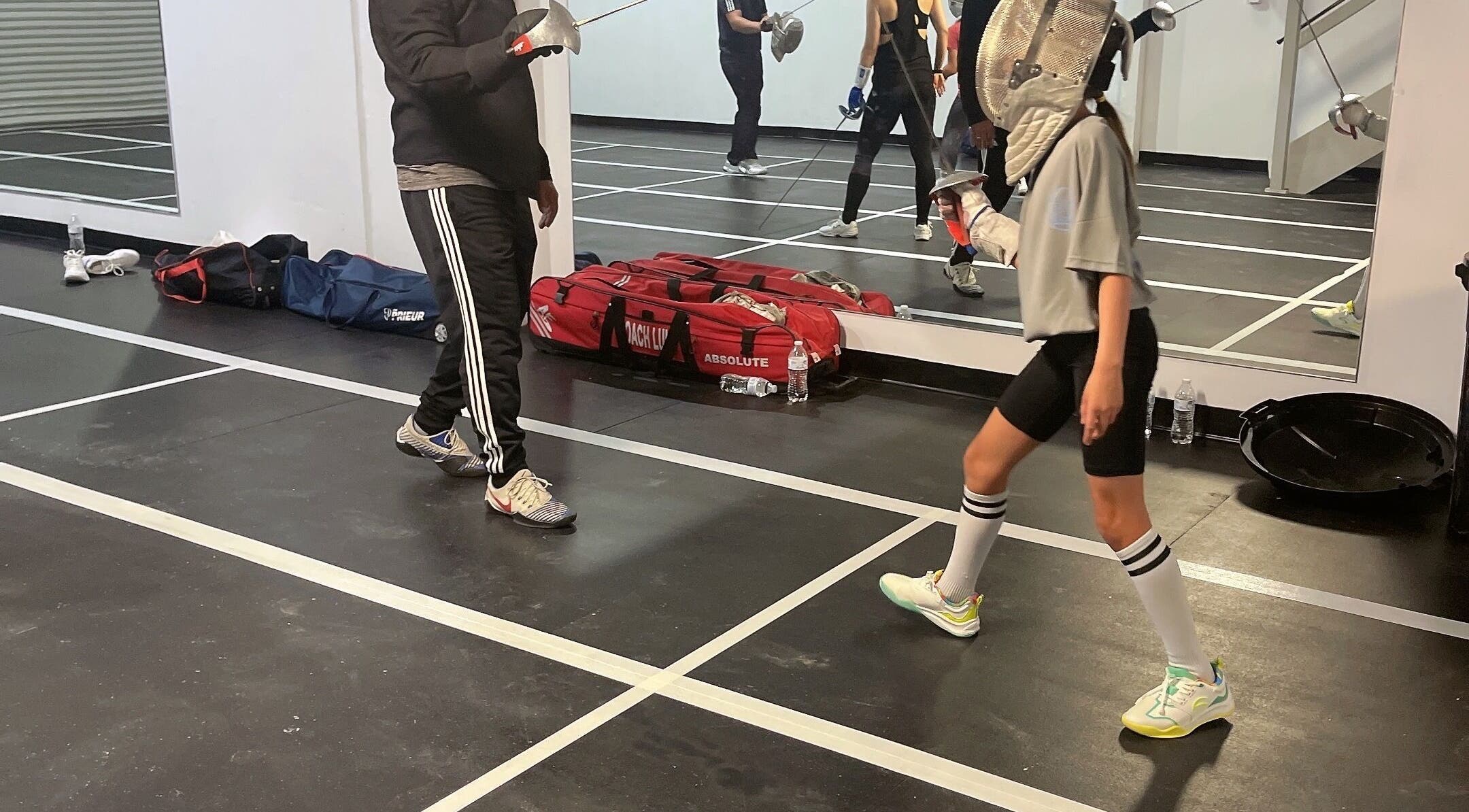 Fencing lesson at Fence MI Fencing Academy in Las Vegas, Nevada, US, showcasing student and coach in action.