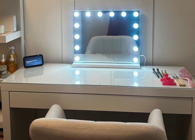 Luxelocksbyizz in Brentwood, England, GB features a chic vanity with illuminated mirror and beauty tools.