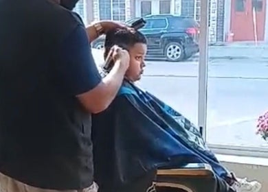 Young boy receives a haircut at Liriano Barber in Monon, Indiana, US, highlighting professional grooming.