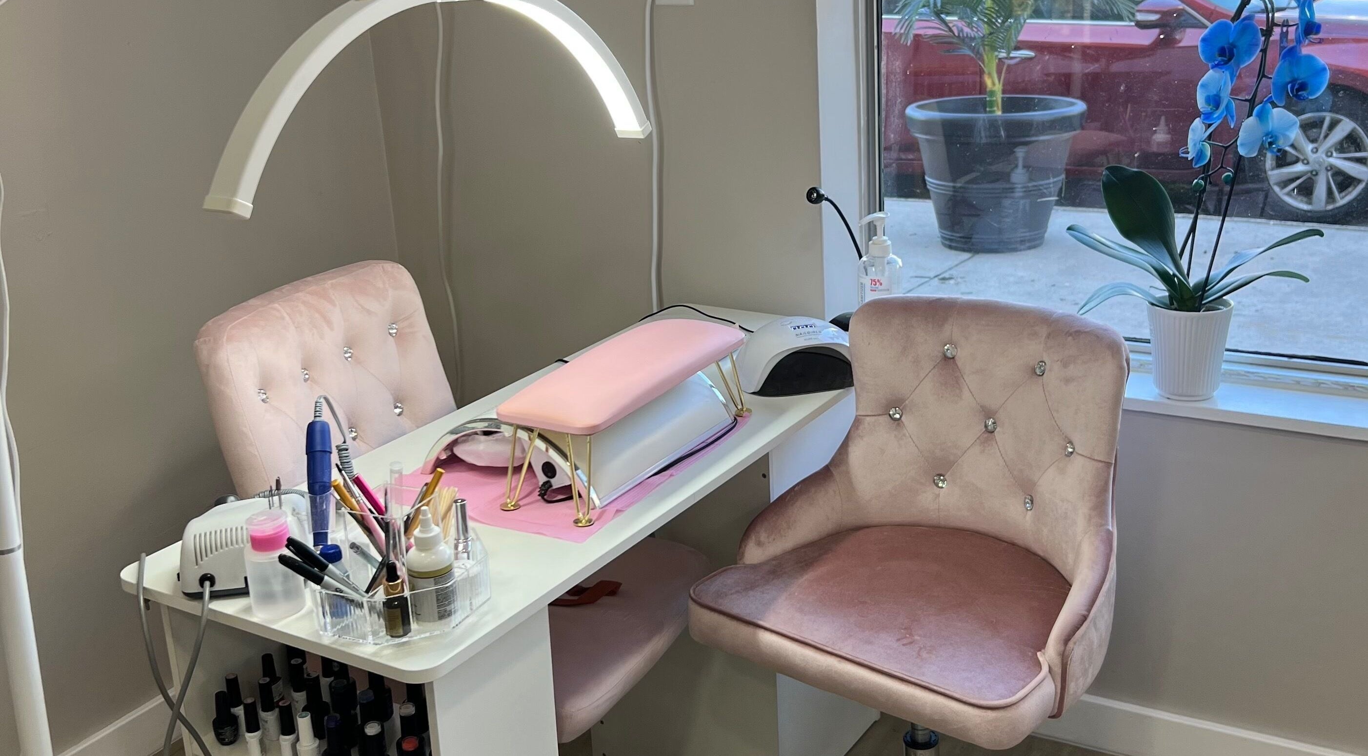Elegant nail station at sam.nailstech, Philadelphia, Pennsylvania, US with plush pink chairs and manicure tools.