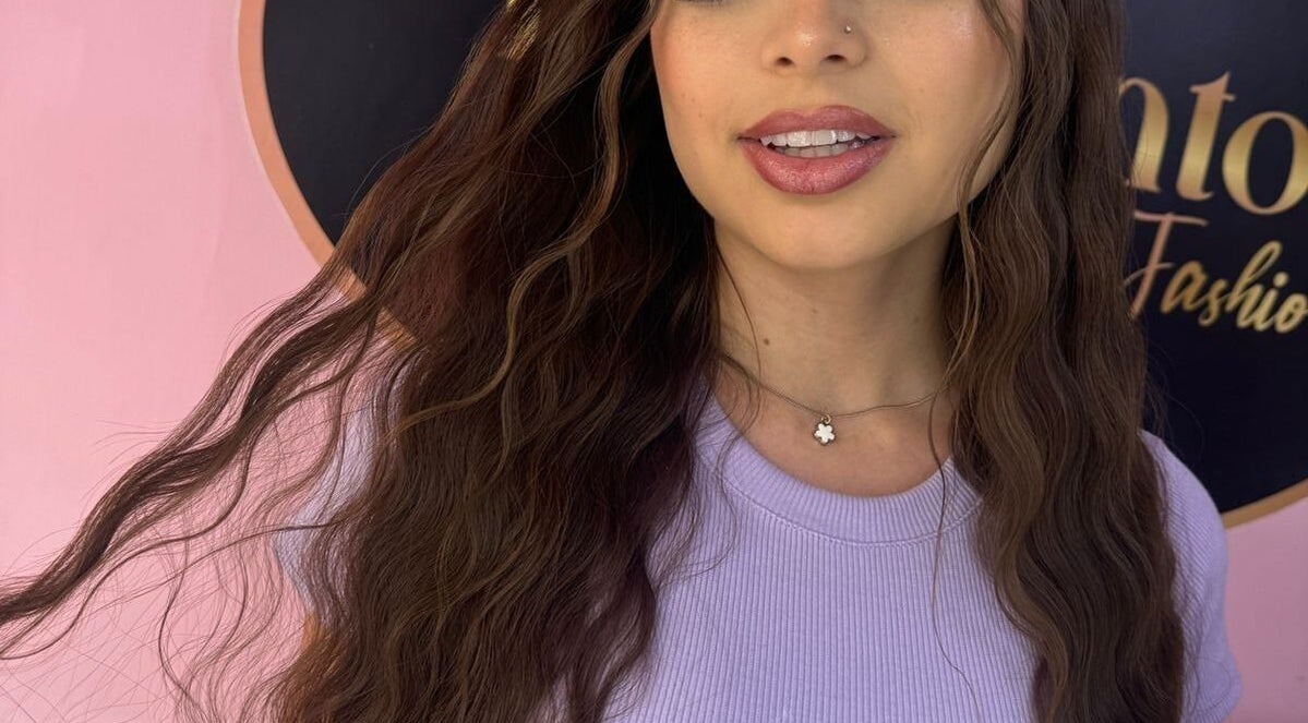 Smiling woman with wavy hair at Pigmentos, La Estrella, Antioquia, CO against a chic background.