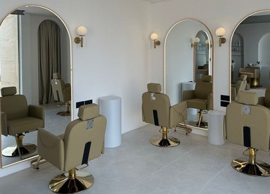 Interior moderno de Elías Guerrero Beauty Salon, Dubái, AE, con sillas beige y espejos grandes.
