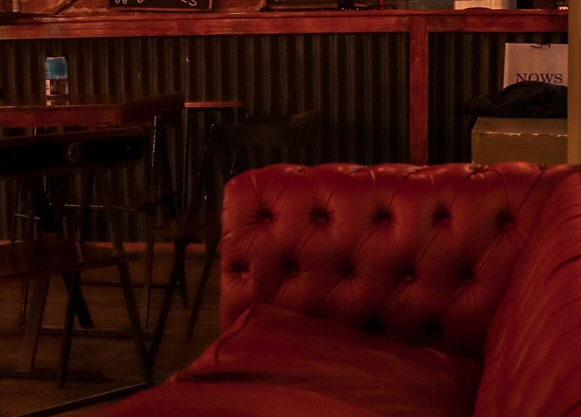 Interior acogedor de Bacanes en San Juan, San Juan, AR, con sofá rojo de cuero y mesas de madera.