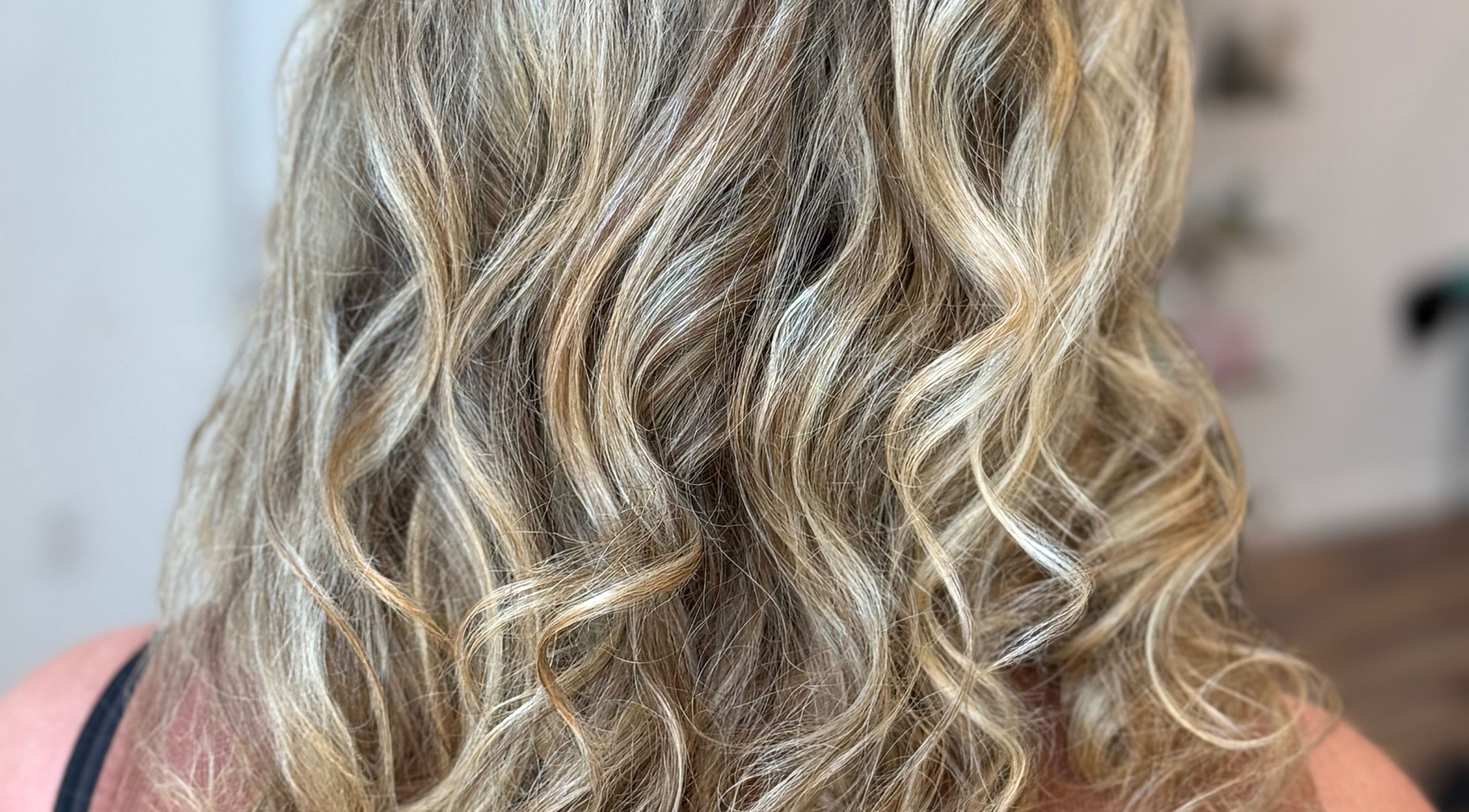 Back view of wavy, blonde hairstyle at Hair To A T By Tee, Arnoldsville, Georgia, US.