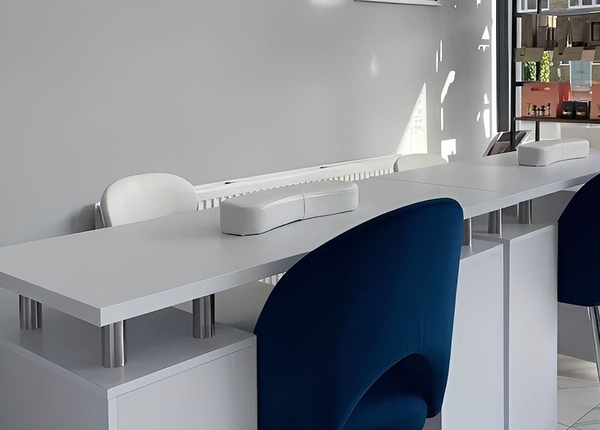 Modern manicure setup at Studio N in West Wickham, England, GB featuring sleek white tables and blue chairs.