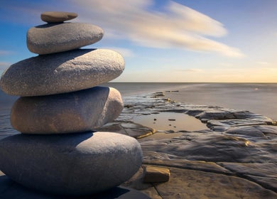 Balanced stones on shore at Think2be Healthy, North Lakes, Queensland, AU. Embrace tranquility by the sea.