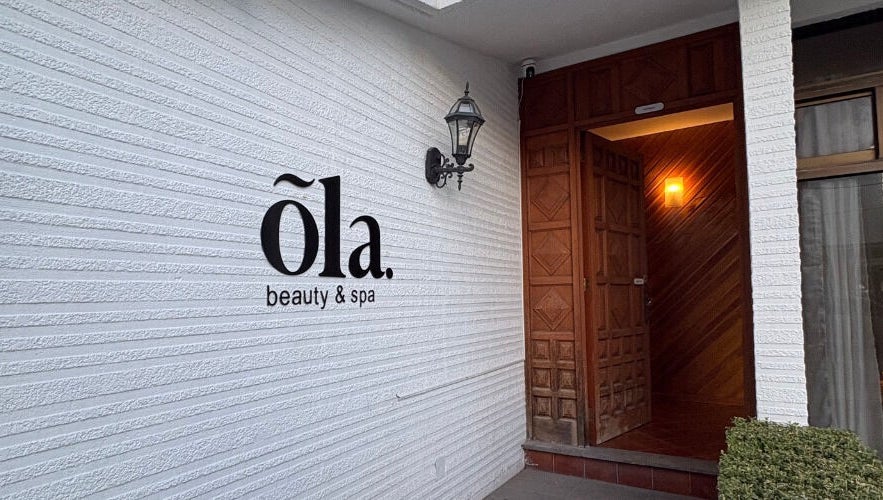 Fachada de Ola Beauty & Spa en Pachuca De Soto, Hidalgo, MX con puerta de madera y lámpara elegante.