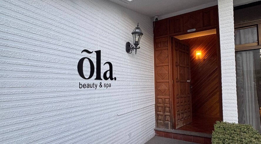 Fachada de Ola Beauty & Spa en Pachuca De Soto, Hidalgo, MX con puerta de madera y lámpara elegante.