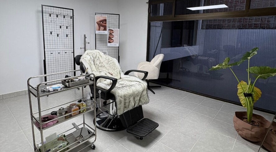 Sala de tratamiento en Ola Beauty & Spa, Pachuca De Soto, Hidalgo, MX con silla y planta decorativa.