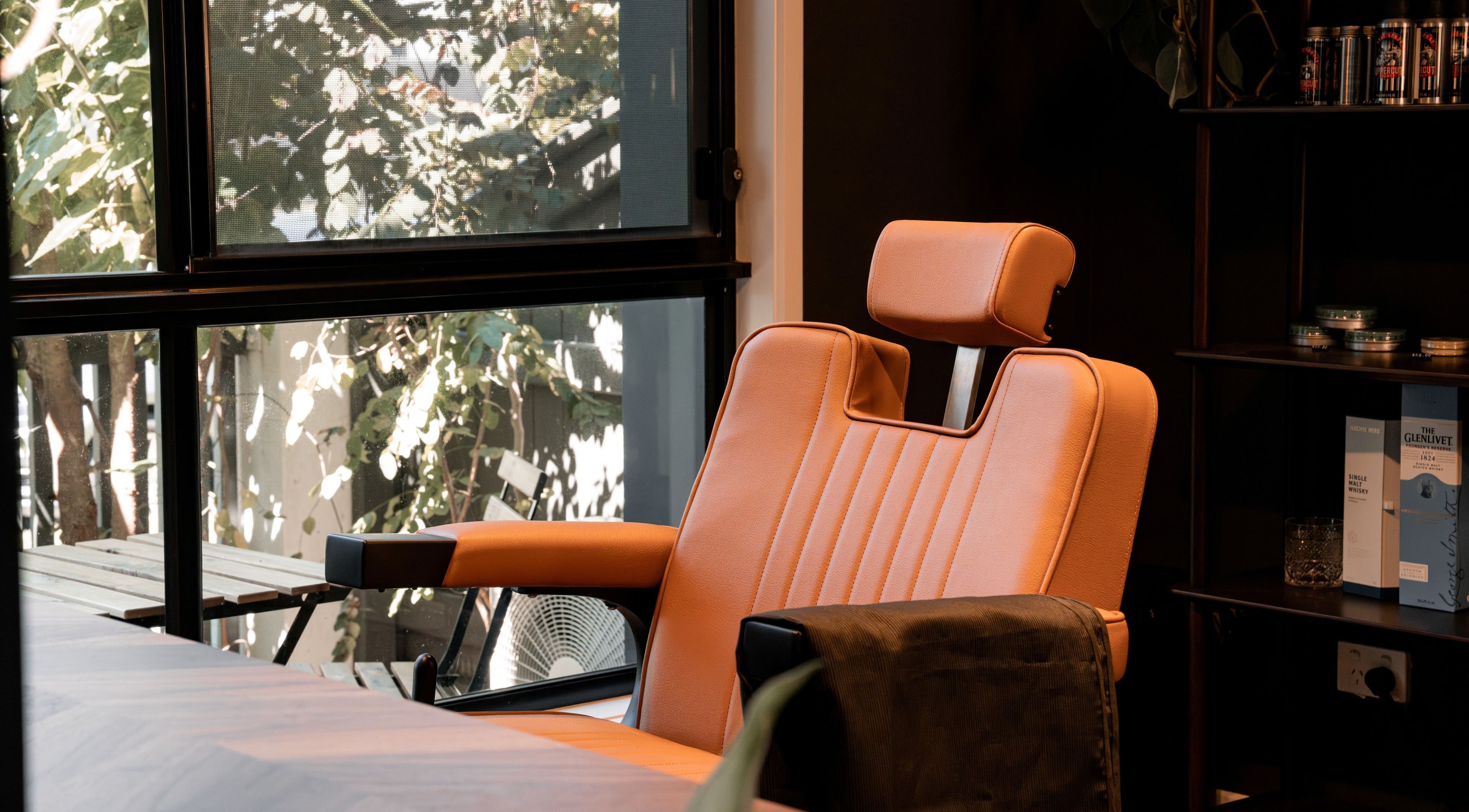 Comfortable barber chair at Caleb Sweeney Barber, Nirimba, Queensland, AU, by a sunlit window.
