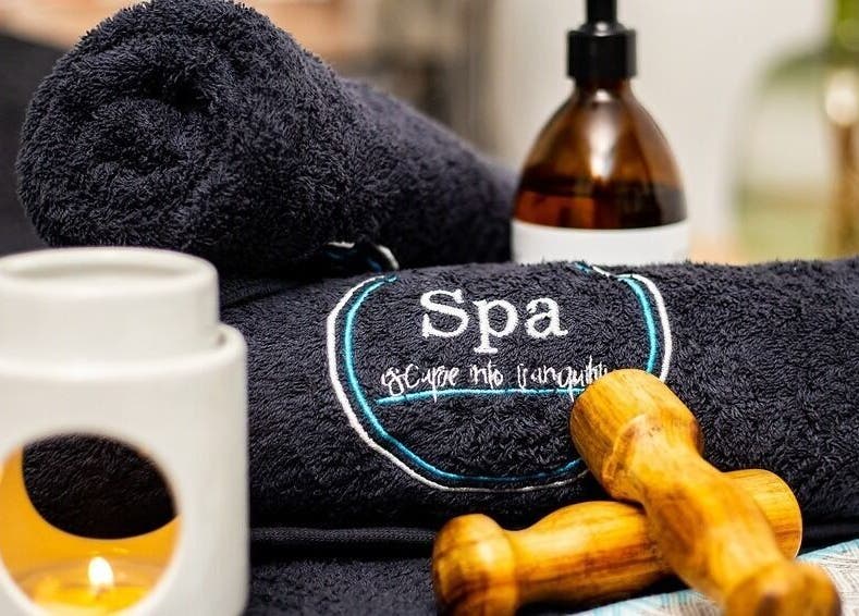 Spa essentials at Spa@primevenue, Lusaka, Lusaka Province, ZM, featuring towels, candle, and massage tool.