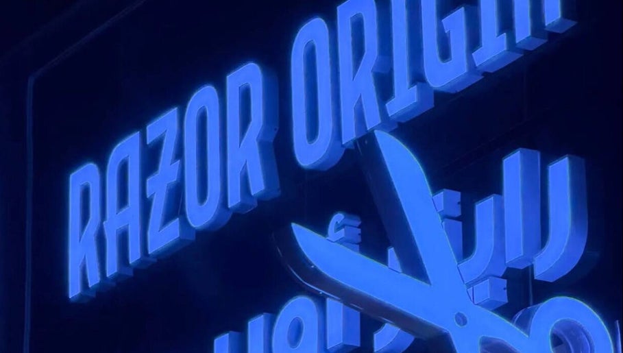 Illuminated Razor Origin Barbershop sign with scissors in Buqayq, Eastern Province, SA.