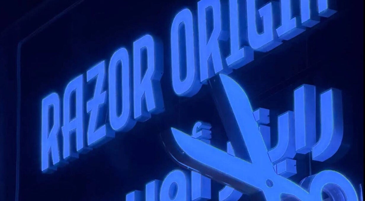 Illuminated Razor Origin Barbershop sign with scissors in Buqayq, Eastern Province, SA.