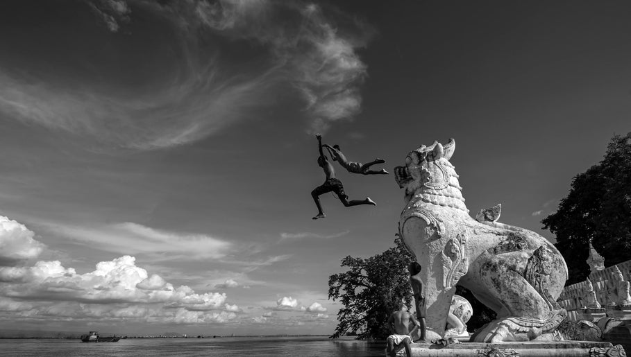 Two kids leap into a river from a lion statue near B M Co, Tanauan City, Calabarzon, PH.