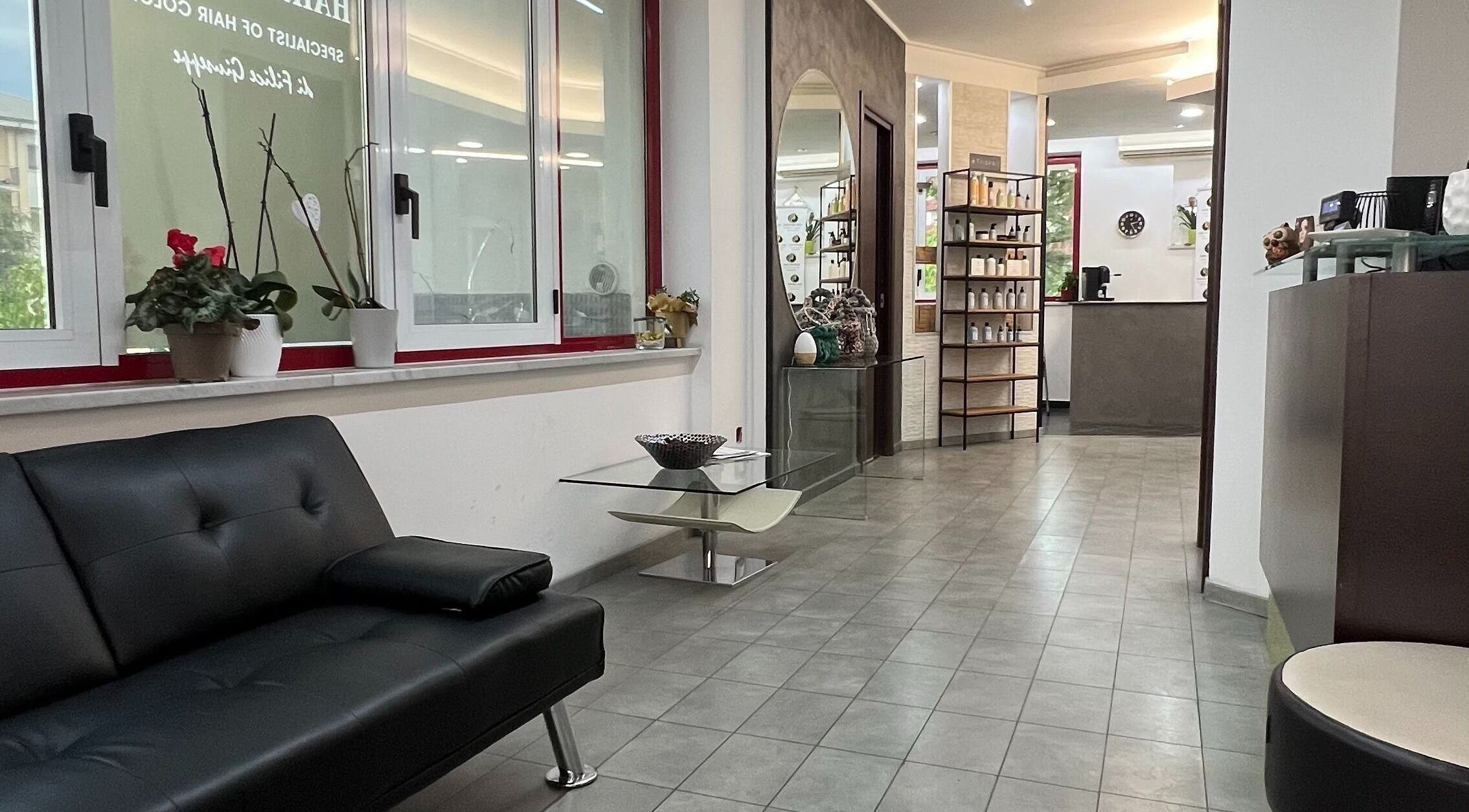 Interno accogliente di Hair Identity, Roges, Calabria, IT, con divano nero e vetrina prodotti.