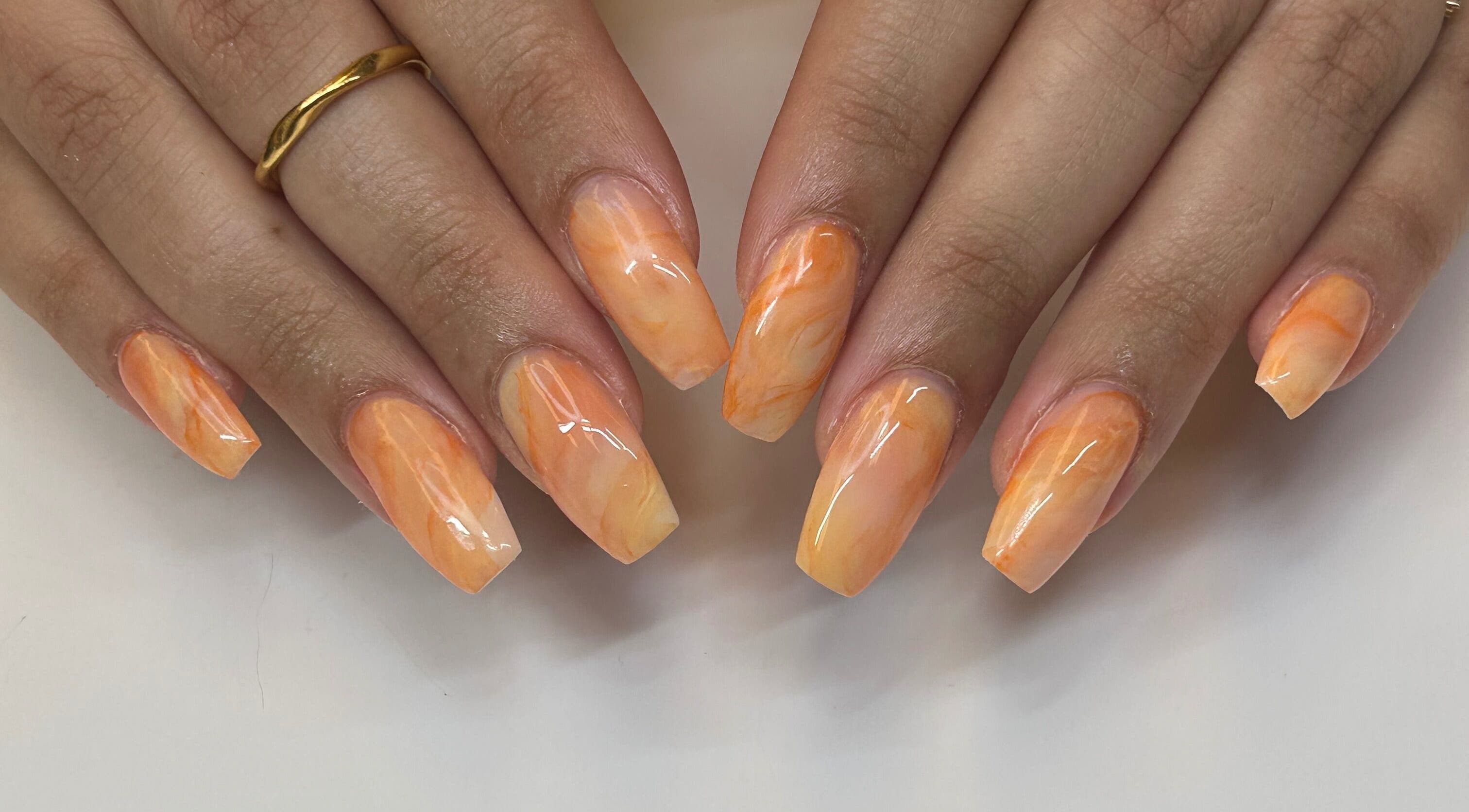 Manucure éclatante à Coralie Esthétique, Laval, Québec, CA, avec des nuances orange.