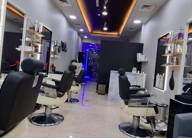 Modern interior of Sparkles N Charms Gents Salon in Dubai, AE showcasing sleek styling chairs and mirrors.