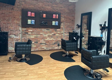 Modern salon interior at Elevate Hair Studio in De Pere, WI, US with stylish chairs and brick walls.
