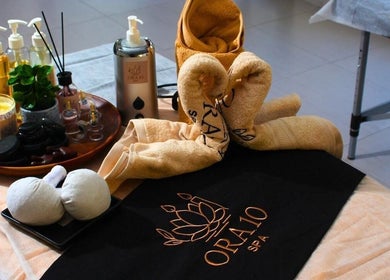 ORA10 SPA - Home Service in Riyadh features a calming treatment setup with oils, towels, and candles.