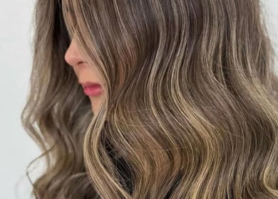 Smooth, wavy hairstyling at Olafol Centre De Beauté, Montréal, Québec, CA showcasing elegant brown highlights.