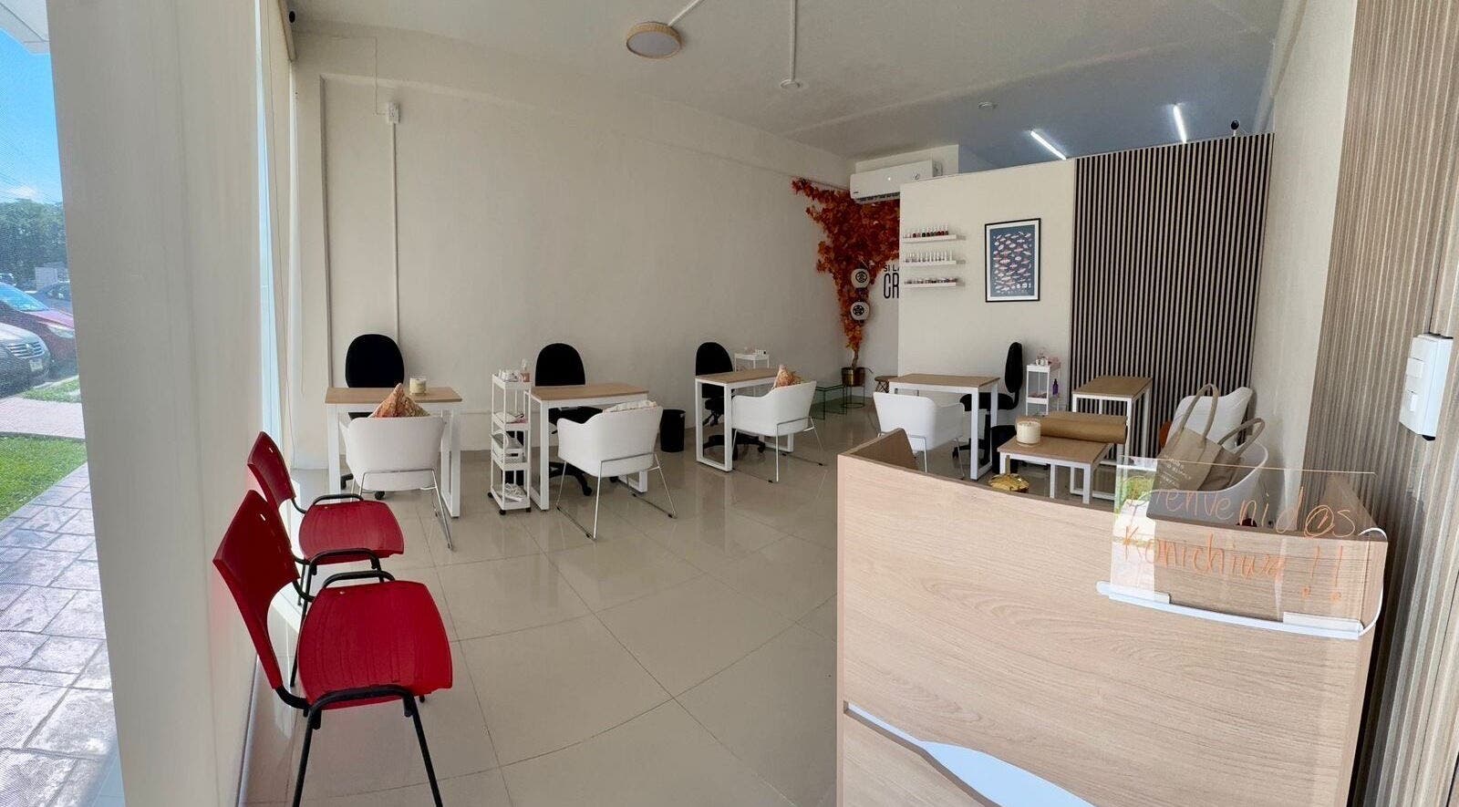 Interior moderno y acogedor de Momiji Nails Time en Mérida, Yucatán, MX con mesas y sillas blancas.