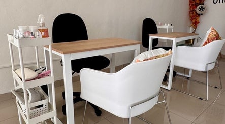 Espacio moderno de uñas en Momiji Nails Time, Mérida, Yucatán, MX, con sillas blancas y mesas elegantes.