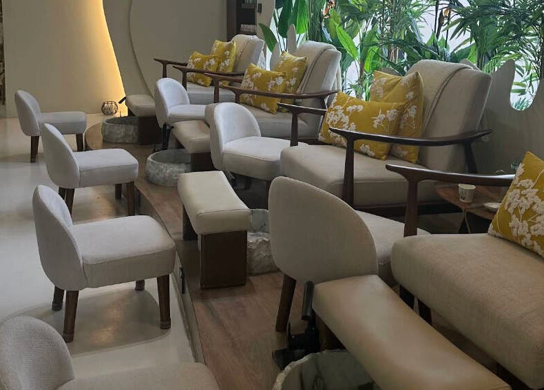 Luxurious pedicure chairs with cushions at Blend Spa, Sharjah, AE, surrounded by lush greenery.