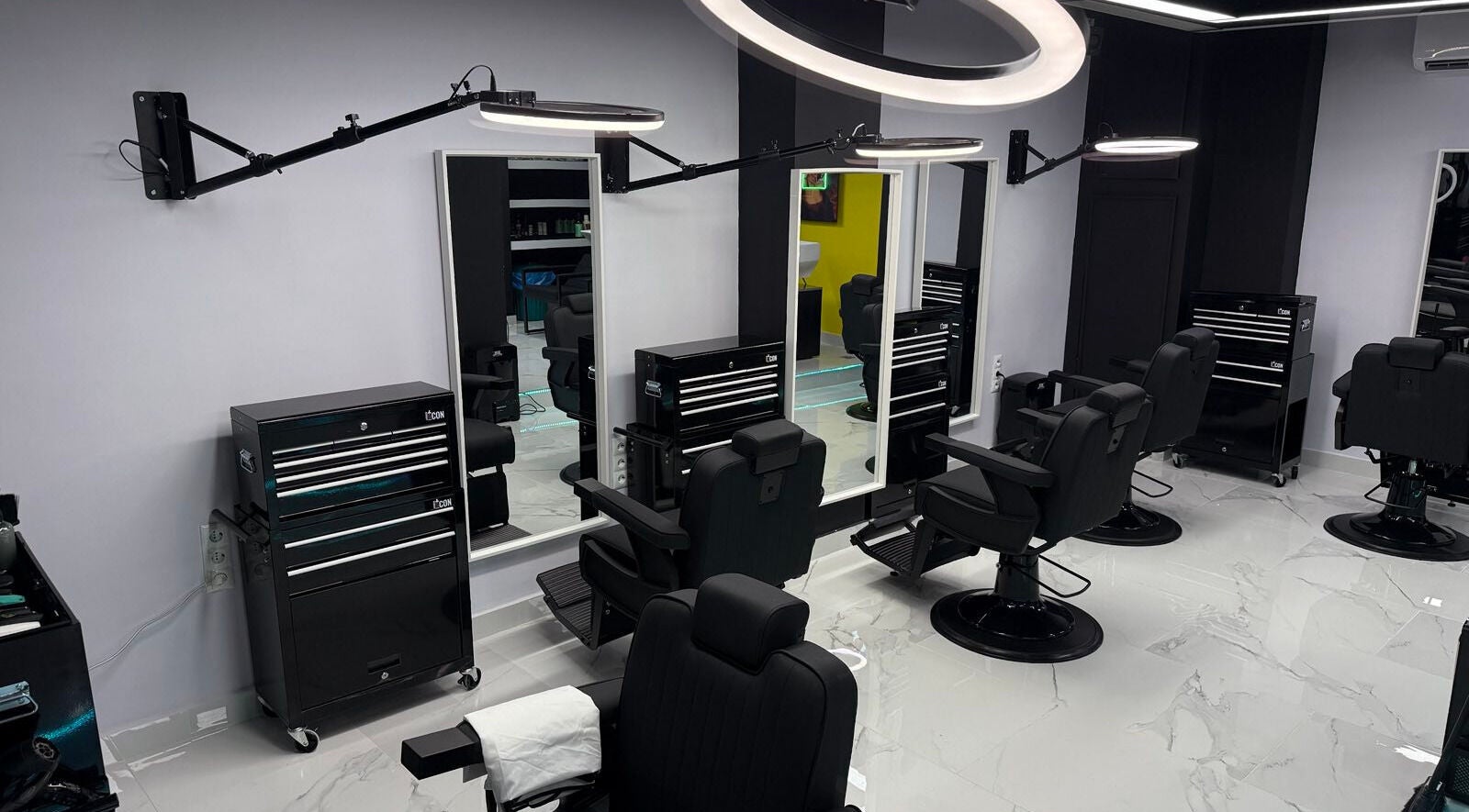 Κομψό εσωτερικό του Anestis Barber στην Αγία Βαρβάρα, GR με μοντέρνες καρέκλες και φωτιστικά.