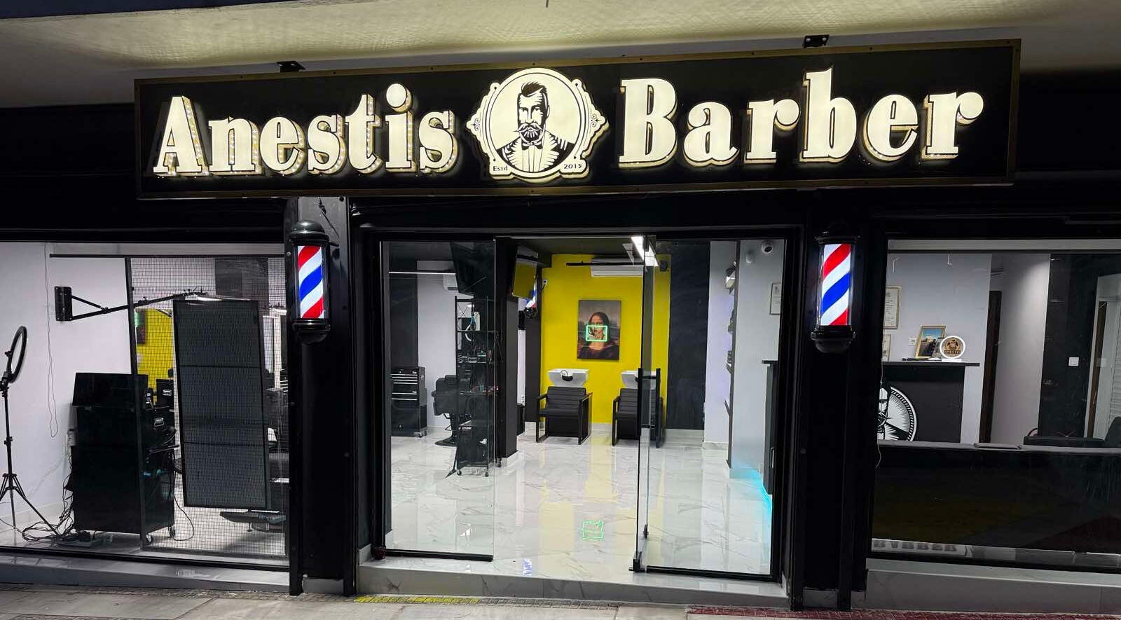 Η πρόσοψη του Anestis Barber στην Αγία Βαρβάρα, GR με φωτεινή επιγραφή και μοντέρνα διακόσμηση.