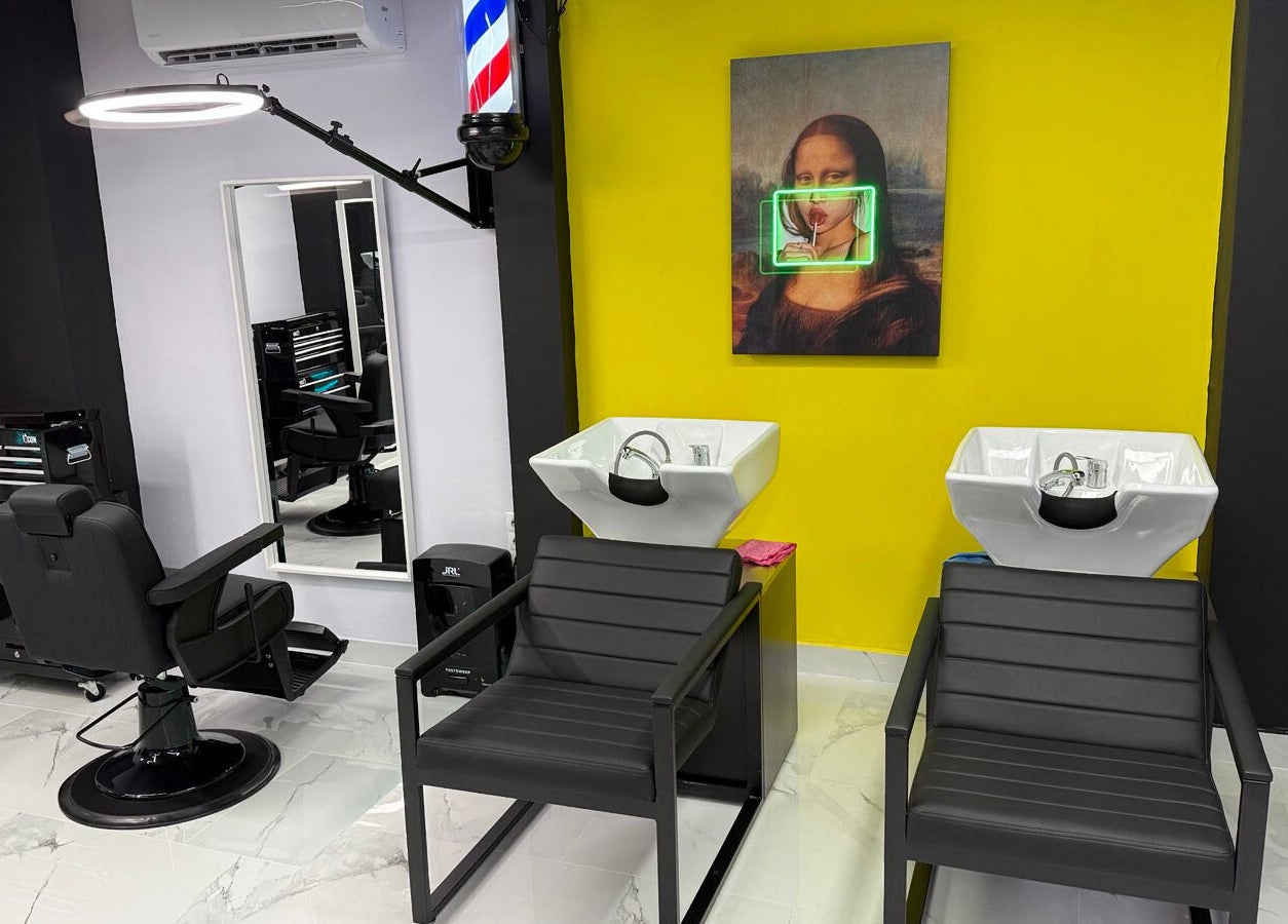 Μοντέρνο εσωτερικό στο Anestis Barber, Agia Varvara, GR με καρέκλες κομμωτηρίου και φωτεινή τέχνη.