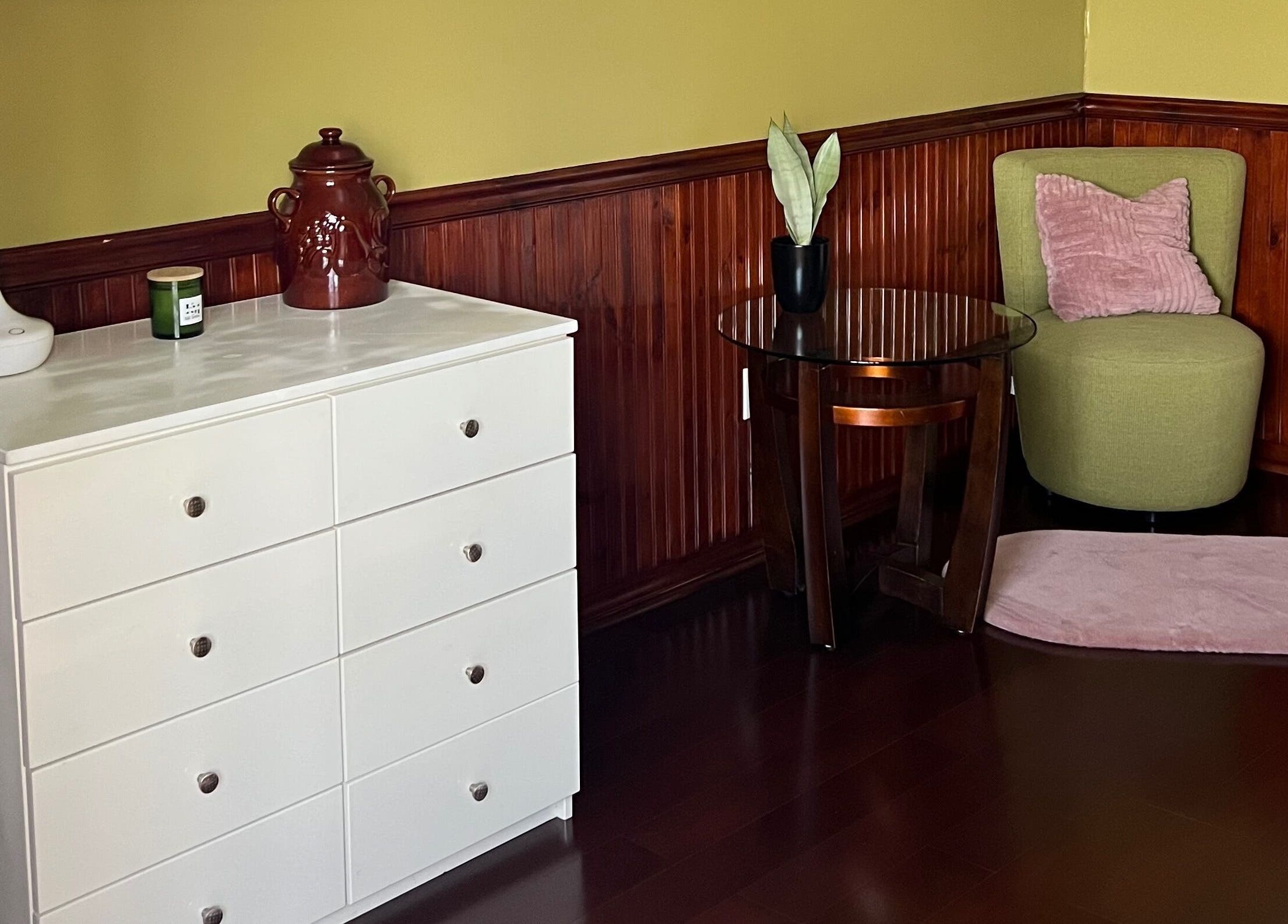 Gezellige hoek bij Marilyn's Wax and Beauty Salon, Paramaribo, met kast, groene stoel en plant.