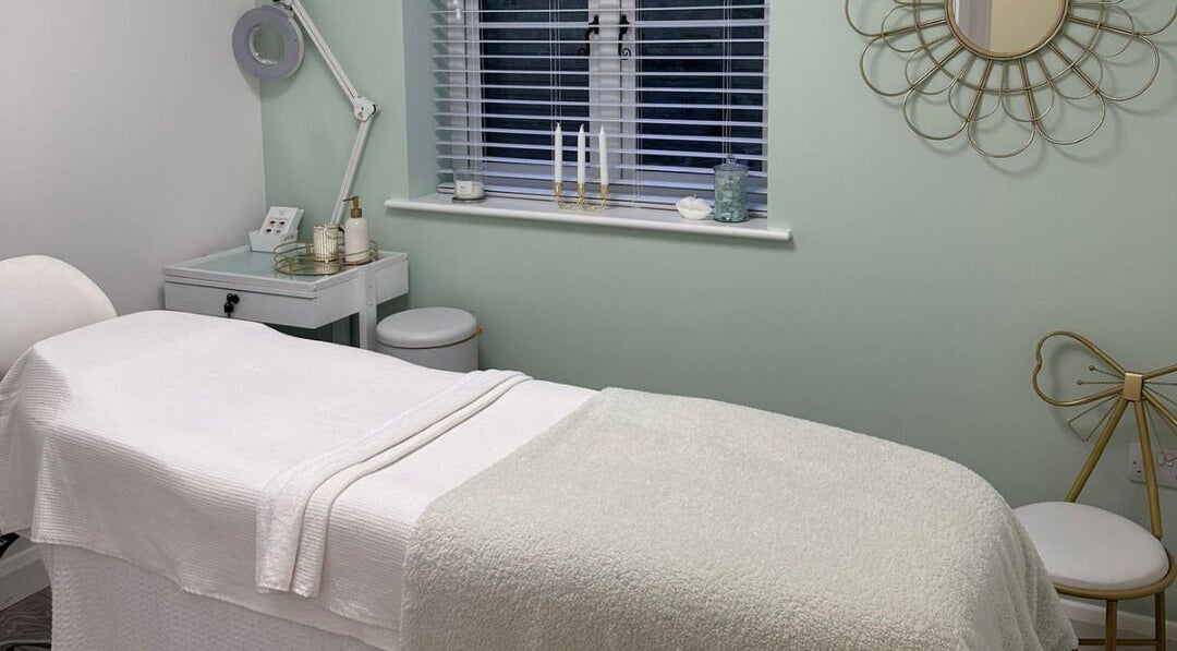 Pure Cosmetics, Botley, England spa room with a treatment bed, mirror, and soothing decor.
