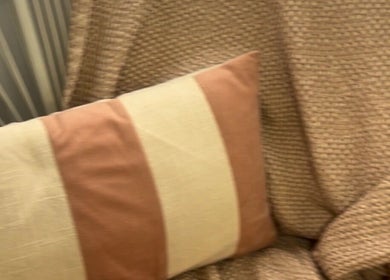 Cozy corner with a striped pillow and textured throws at The Lady Cave, Palmerston North, Manawatū-whanganui Region, NZ.