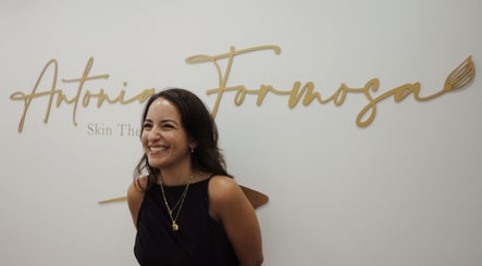 Smiling therapist at Antonia Formosa Skin Therapist, St Julian's, MT with elegant signage background.