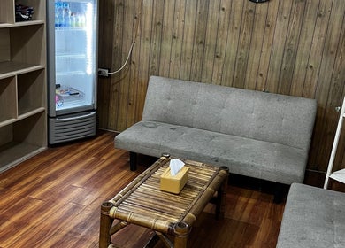 Ruang tunggu nyaman di Barberhop, Sumatera Utara, ID dengan sofa abu-abu dan dekorasi kayu.