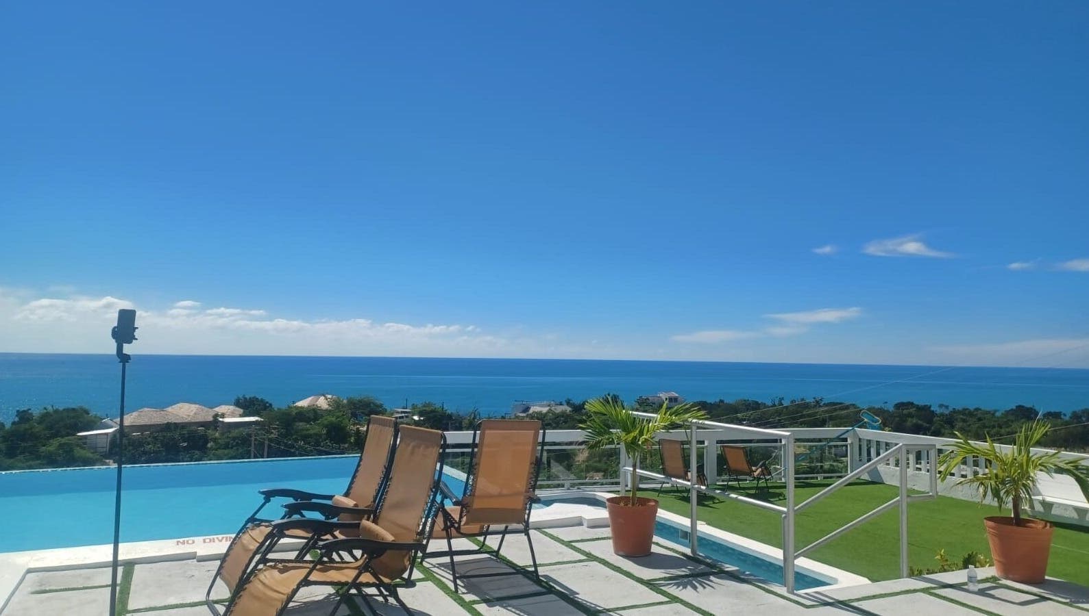 Serene oceanview at Tranquil Travels Mobile Spa, Ocho Rios, JM, showcasing lounge chairs and lush greenery.