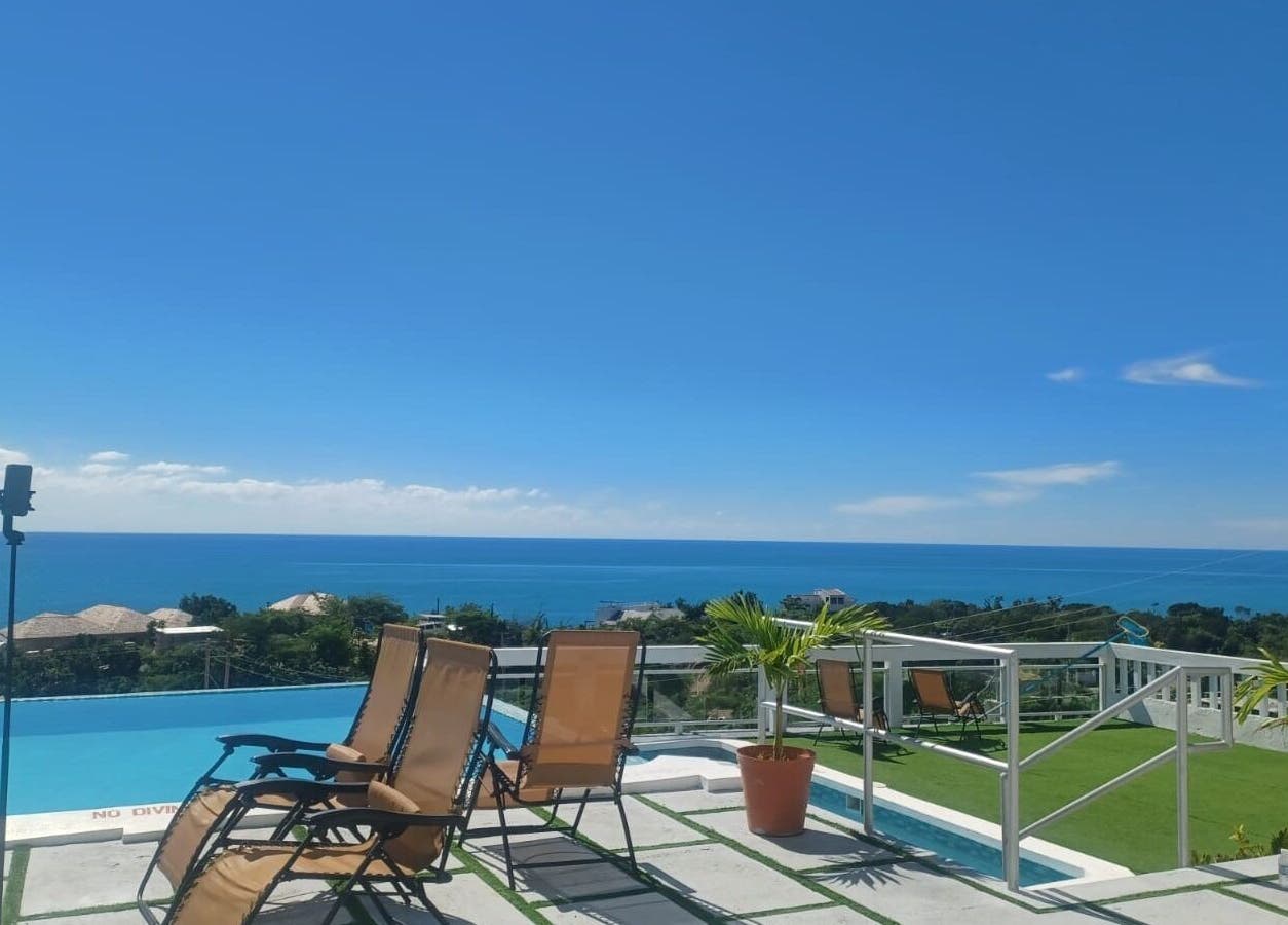 Serene oceanview at Tranquil Travels Mobile Spa, Ocho Rios, JM, showcasing lounge chairs and lush greenery.