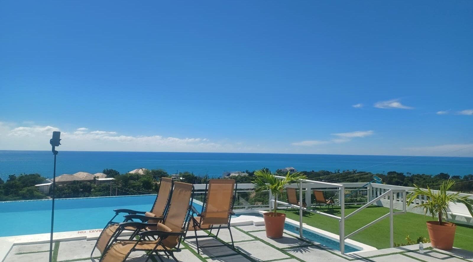 Serene oceanview at Tranquil Travels Mobile Spa, Ocho Rios, JM, showcasing lounge chairs and lush greenery.