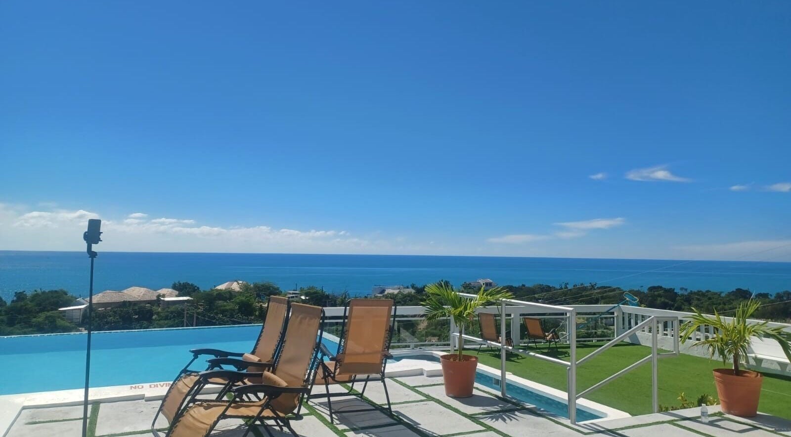 Serene oceanview at Tranquil Travels Mobile Spa, Ocho Rios, JM, showcasing lounge chairs and lush greenery.