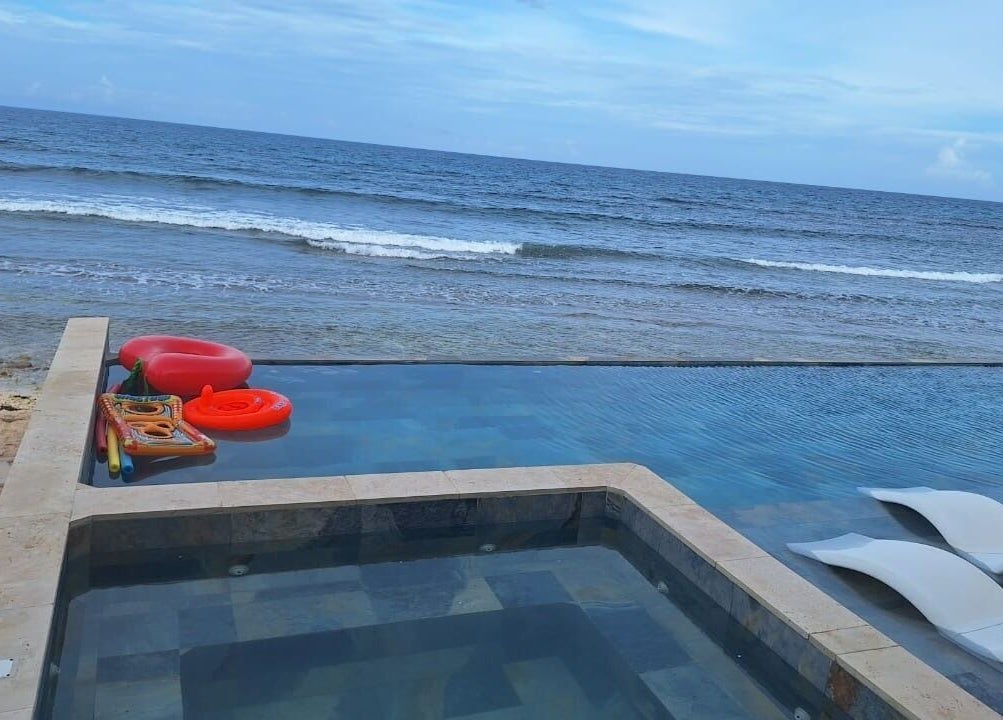 Infinity pool overlooking ocean at Tranquil Travels Mobile Spa, Ocho Rios, JM, featuring poolside loungers.