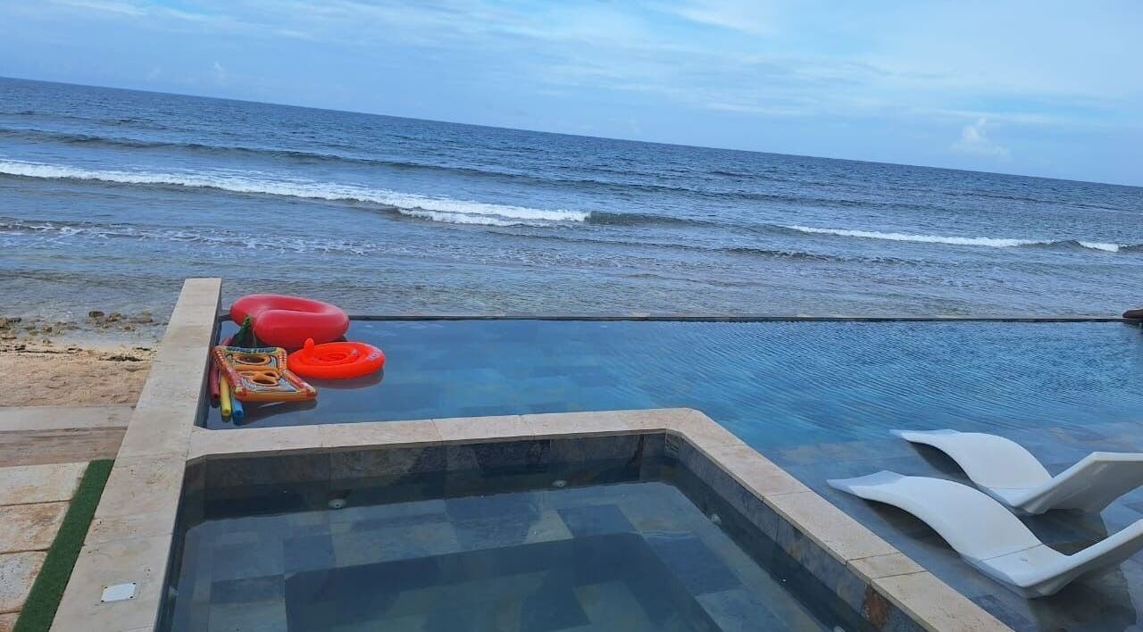 Infinity pool overlooking ocean at Tranquil Travels Mobile Spa, Ocho Rios, JM, featuring poolside loungers.
