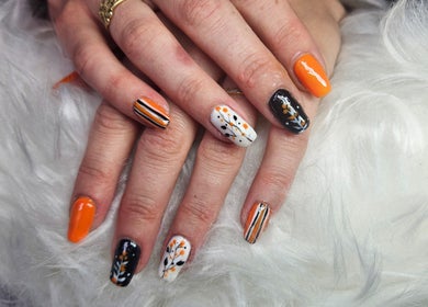 Autumn-themed nail art at Kawaii Nails in Neath, Wales, GB with orange, black, and white designs.