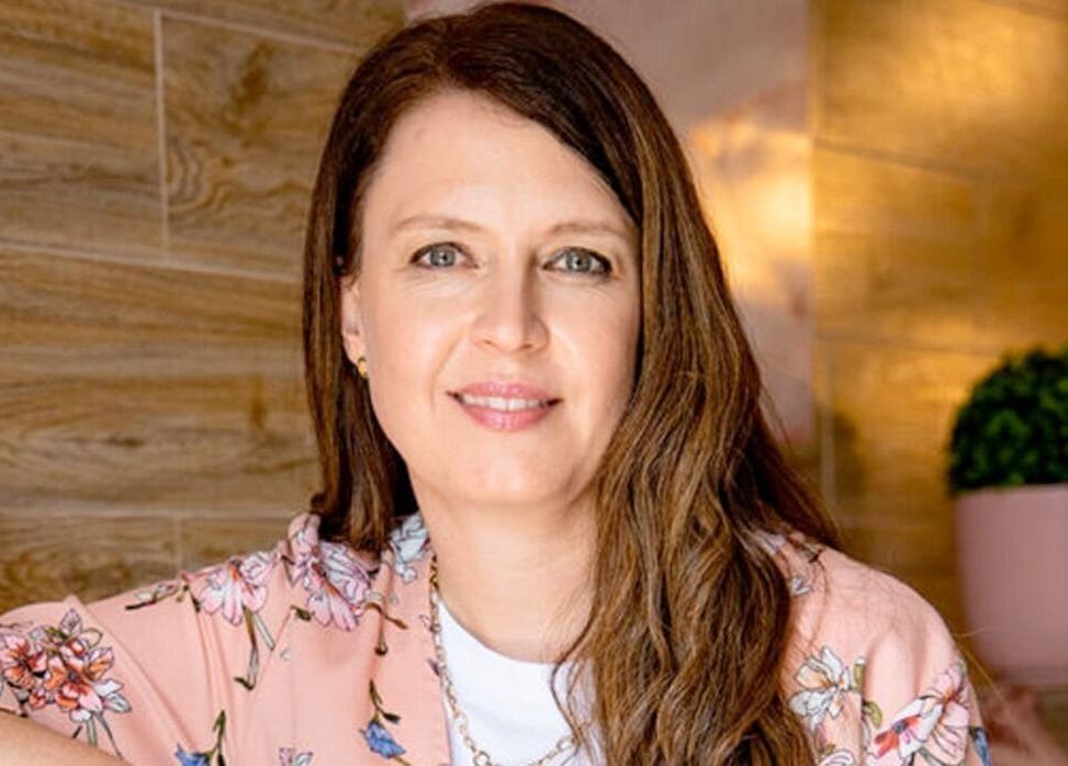 Smiling woman in floral attire at The Lashery George, vibrant decor, George, Western Cape, ZA.