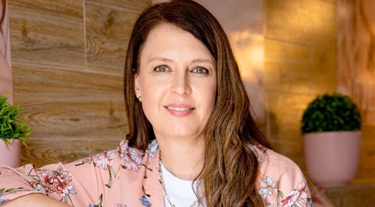 Smiling woman in floral attire at The Lashery George, vibrant decor, George, Western Cape, ZA.