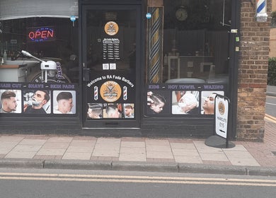 Exterior of RA FADE BARBERS in London, England, GB showcasing hair services and opening hours.