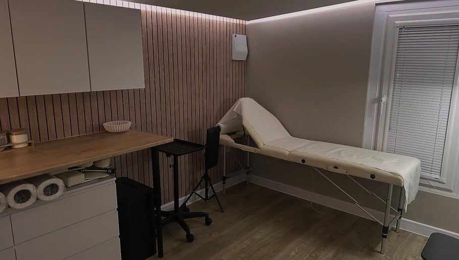 Cozy treatment room at Silk Touch Tattoos, Colchester, England, GB featuring a massage table and wooden accents.