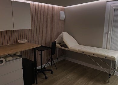 Cozy treatment room at Silk Touch Tattoos, Colchester, England, GB featuring a massage table and wooden accents.