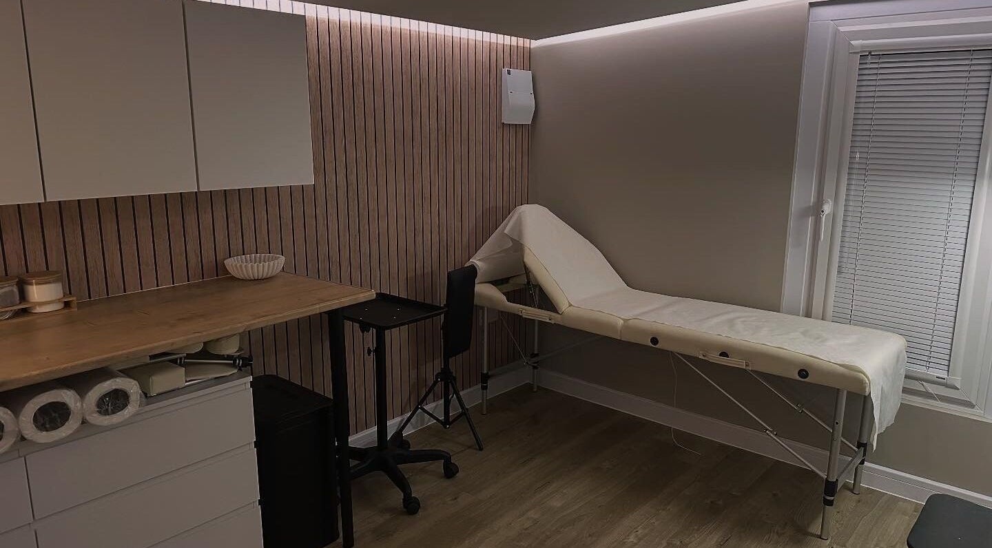 Cozy treatment room at Silk Touch Tattoos, Colchester, England, GB featuring a massage table and wooden accents.